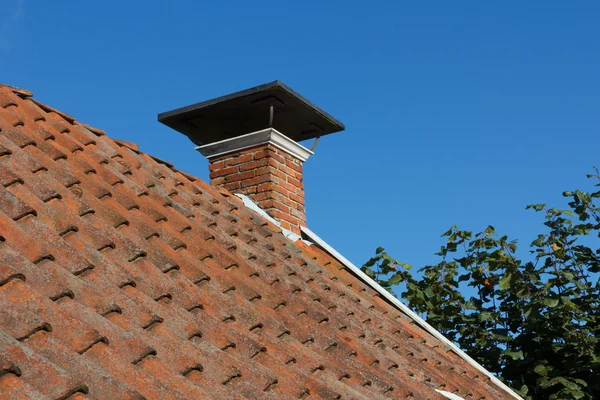 Brick chimney with cap on tiled roof
