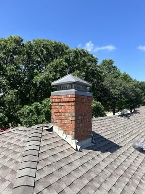 Brick chimney with metal cap on shingle roof
